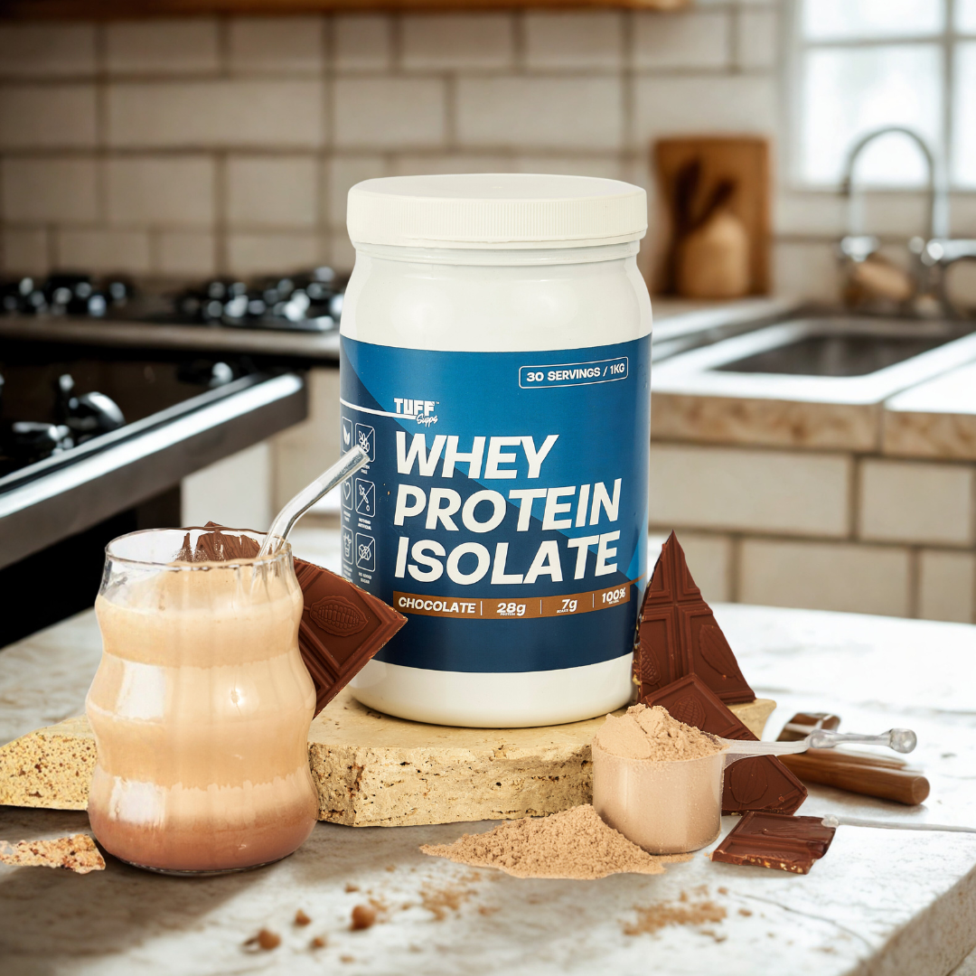 tuff supps Whey protein isolate container with a glass of chocolate protein shake on a kitchen counter.