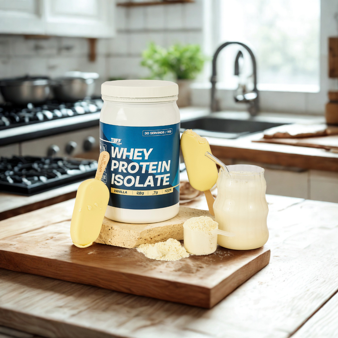 tuff supps Whey protein isolate container on a kitchen counter with a glass of milk and a scoop.